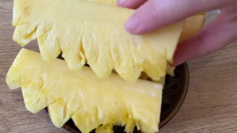 Juicy pieces of slice ripe pineapple stand on a plate on the table a female hand Stock Footage 308776916