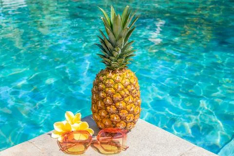 Juicy pineapple and glasses by the pool. Summer concept. Stock Photos