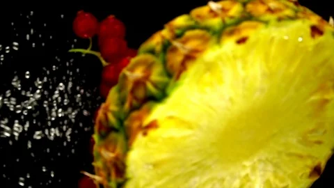 Juicy pineapple and red currant dropped into the water Video stock 77749008