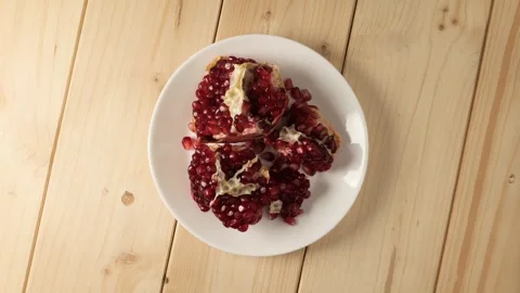 Juicy pomegranate fruit rotating on a white plate Stock Footage 340160076