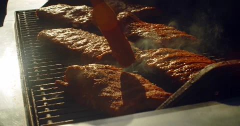 Juicy rack of ribs being basted and cooking on a bbq grill on a summer afternoon Stock-Footage 133440385