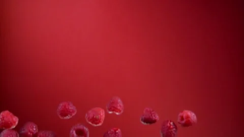 Juicy raspberries bouncing up on a red background Stock Footage 121364837