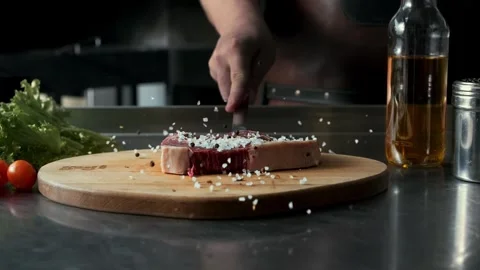 Juicy raw marbled beef steak falls on a cutting board in spices in slow motion Stock Footage 314577060