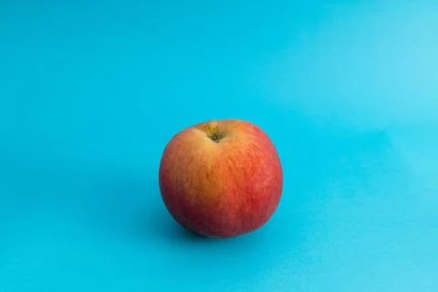 Juicy red apple on blue background, subject food shot Stock Photos