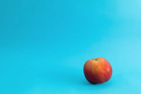 Juicy red apple on blue background, subject food shot Stock Photos