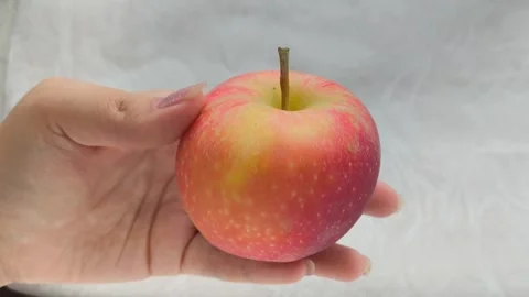A juicy red apple with a green leaf in a womans hand. Juicy fruits. Stock Footage 314976383