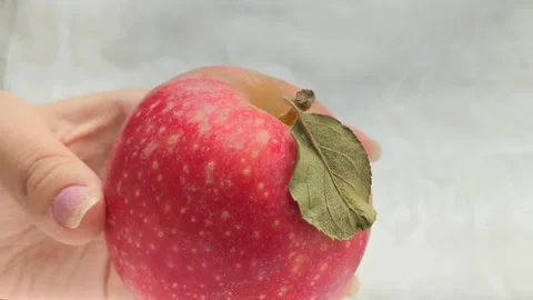 A juicy red apple with a green leaf in a womans hand. Juicy fruits. Stock Footage 314976468
