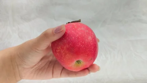 A juicy red apple with a green leaf in a womans hand. Juicy fruits. Stock Footage 314976505