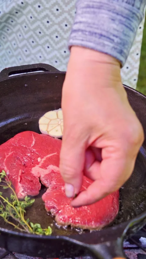 Juicy, red steak is being cooked in a cast iron pan outside on the grill. Stock Footage 315269207