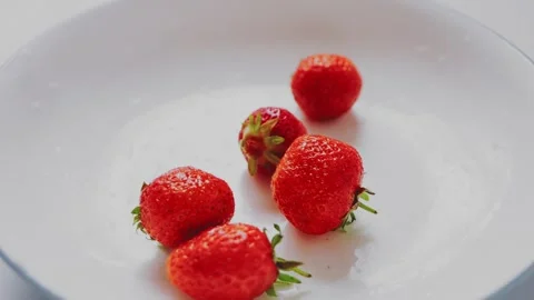Juicy red strawberries fall into a white plate top view Vidéo 246233073