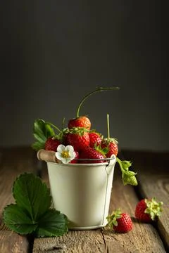 Juicy red strawberries in a mini bucket on a wooden background Stock Photos