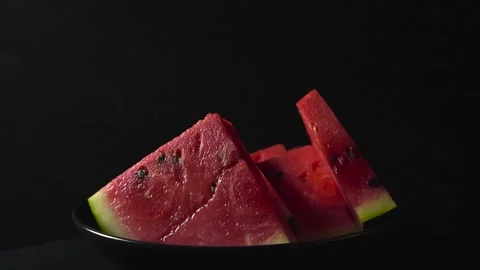 Juicy red watermelon slices rotating on black background Stock Footage 340554997