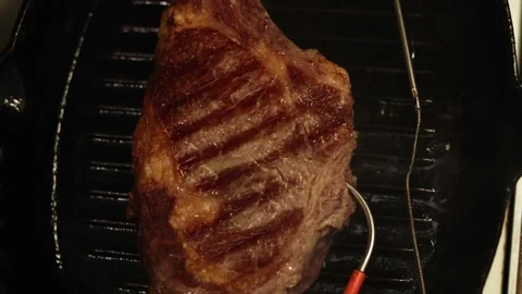 Juicy ribeye steak seared on a grill pan with thermometer Stock Footage 340563192