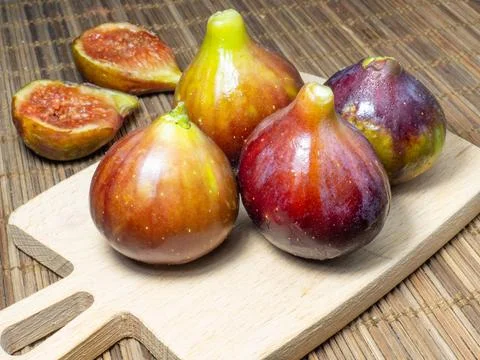 ?Juicy ripe figs on a cutting board. Halves of figs. Southern fruits on the t Stock Photos