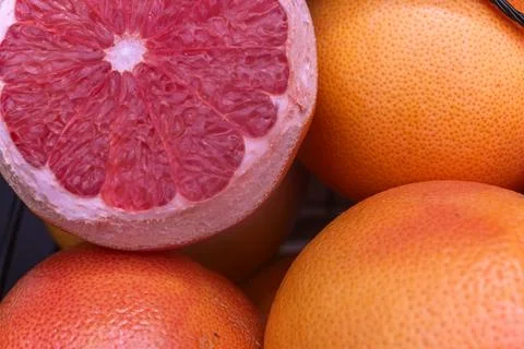 Juicy ripe ruby red grapefruit cut in half close up on organic whole pink c.. 写真素材