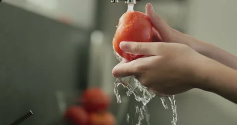 Juicy ripe tomato is washed under water from the kitchen tap Stock Footage 252027666
