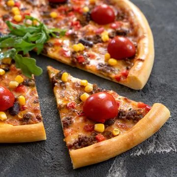 Juicy slice of meat pizza with corn and tomato on black background. Close up Stock Photos