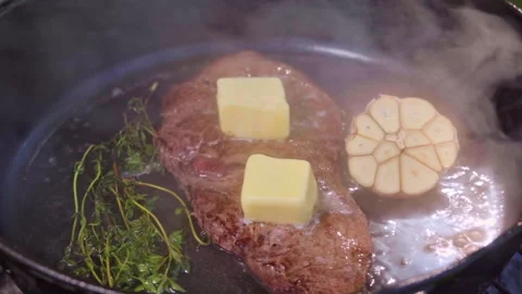 Juicy steak is being cooked in a cast iron pan outdoors on the grill. Stock Footage 315404991