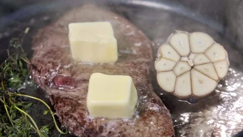 A juicy steak being cooked in olive oil with butter, garlic and thyme. Stock Footage 315279205