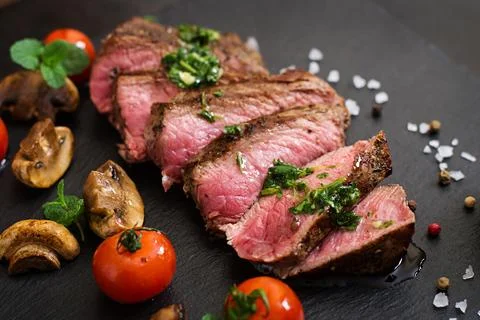 Juicy steak medium rare beef with spices and grilled vegetables. Stock Photos