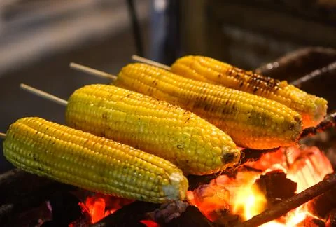 Juicy Sweet Corn Cobs Being Roasted Over Fire Flame in Traditional Stall Stock Photos