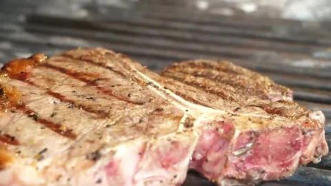 Juicy T-Bone Steak Grilling on Barbecue with Grill Marks, Close-up Stock Footage 338213176
