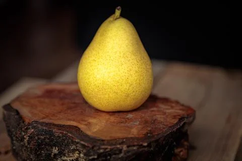 Juicy yellow pear on a wooden background from old boards in a low key. Stock Photos