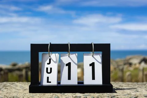 Jul 11 calendar date text on wooden frame with blurred background of ocean. Stock Photos