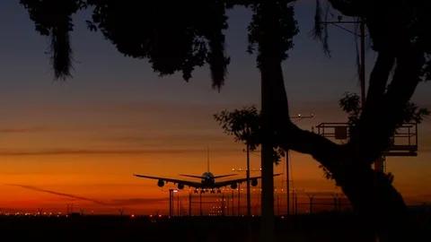 Jumbo jet Airbus A380 plane landing against an orange sunset sky at LAX airport Stock Footage 83897215