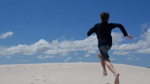 Jump off face of the earth, athletic jump in the dunes Stock Footage 106938404