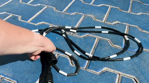 The jump rope is lying on the ground, and a woman's hand picks it up Stock Footage 289144587