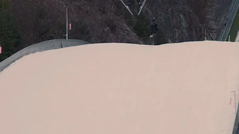 Jumper sliding down on a curved ram on ski jumping venue Stock Footage 170434172