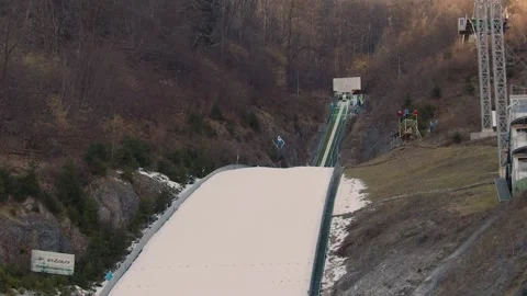 Jumper sliding down on a curved ram on ski jumping venue Stock Footage 170436875