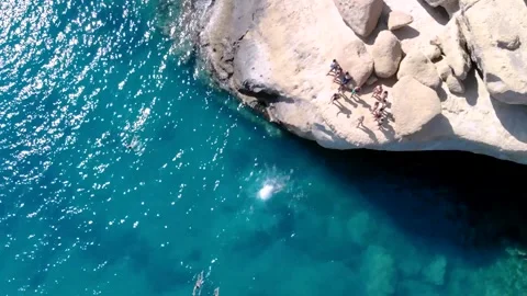 Jumping down a rocky cliff into the mediterranean ocean Stock Footage 261062114