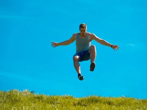 Jumping up guy. Background blue sky. Below the green grass Stock Photos