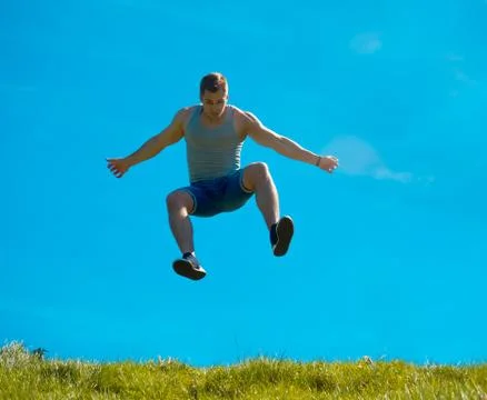 Jumping up guy. Background blue sky. Below the green grass Stock Photos