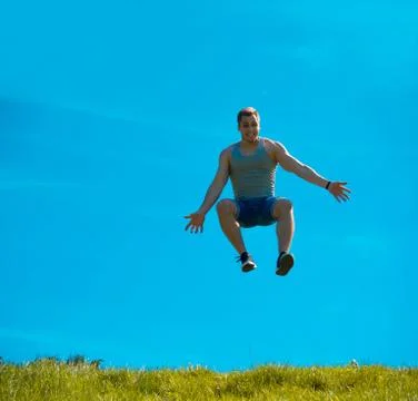Jumping up guy. Background blue sky. Below the green grass Stock Photos