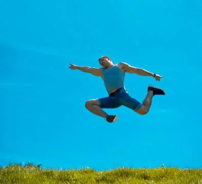 Jumping up guy. Background blue sky. Below the green grass Stock Photos