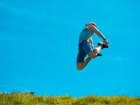 Jumping up guy. Background blue sky. Below the green grass Stock Photos
