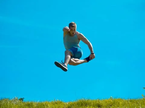 Jumping up guy. Background blue sky. Below the green grass Foto stock