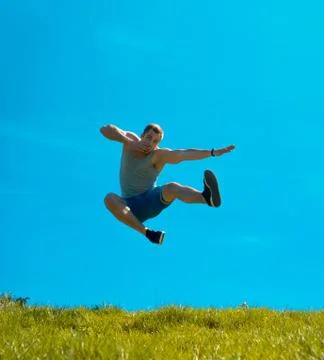 Jumping up guy. Background blue sky. Below the green grass Foto stock