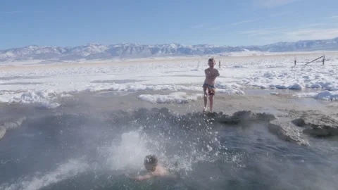 Jumping into a hot water spring in the winter Stock Footage 289357428