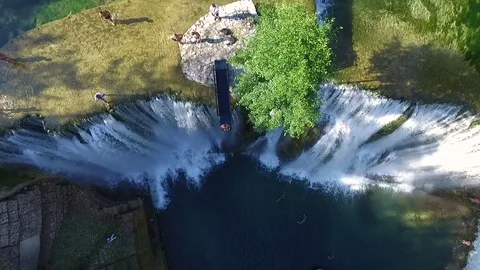 Jumping into river over waterfall in Jajce. Aerial View Slow Motion. Young Man Video stock 80325675