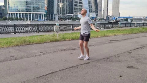 Jumping rope of a young, bald man against the background of business centers Stock Footage 201303360