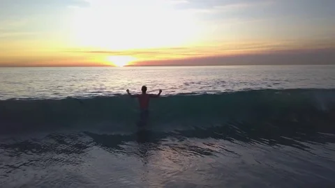 Jumping Through Wave at Sunset 스톡 동영상 83899779
