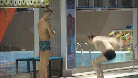 Jumps back into the water.young guy is jumping into the swimming pool. Video stock 134729415