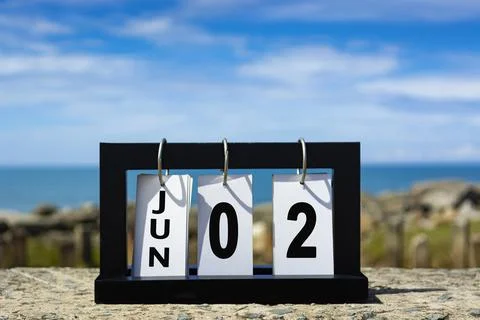 Jun 02 calendar date text on wooden frame with blurred background of ocean. Stock Photos