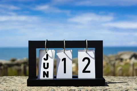 Jun 12 calendar date text on wooden frame with blurred background of ocean. Stock Photos