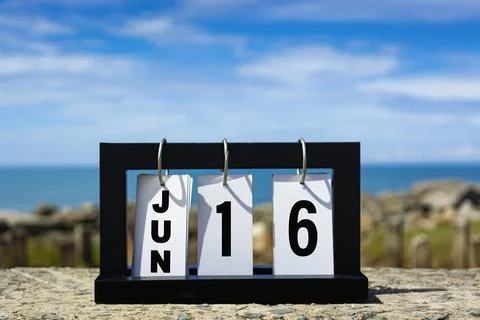 Jun 16 calendar date text on wooden frame with blurred background of ocean. Stock Photos