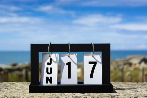 Jun 17 calendar date text on wooden frame with blurred background of ocean. Stock Photos
